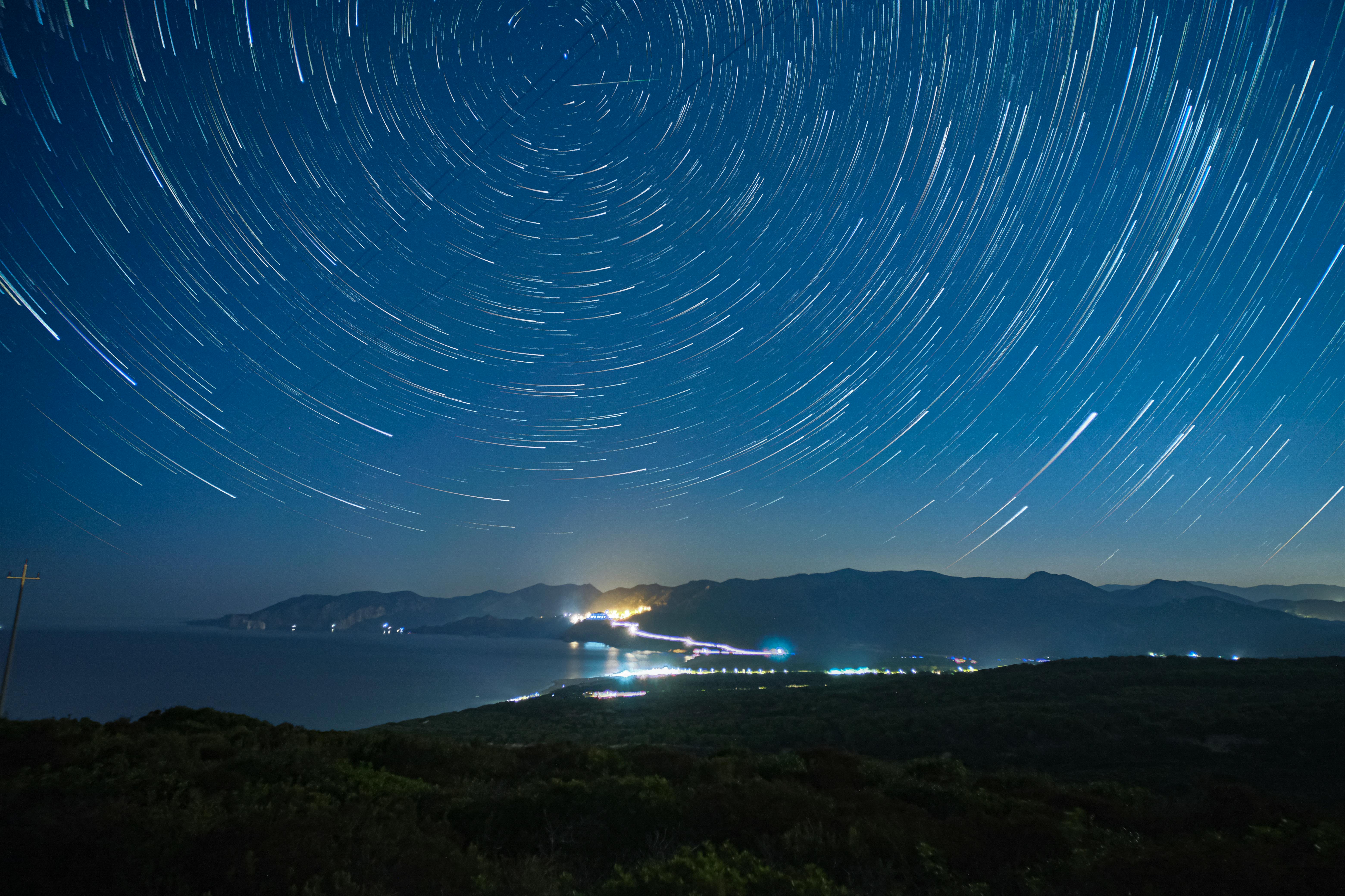silhouette of mountains under blue starry sky in time lapse photography