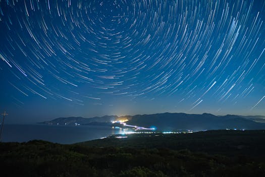 Long exposure of star trails over mountains and coastline at night in Sardinia, Italy.