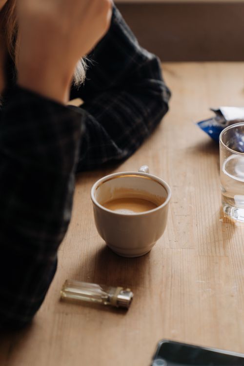 Free Close-up of a warm coffee cup on a wooden table with natural lighting. Stock Photo