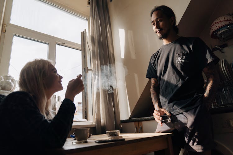 A Couple Talking To Each Other In The Kitchen