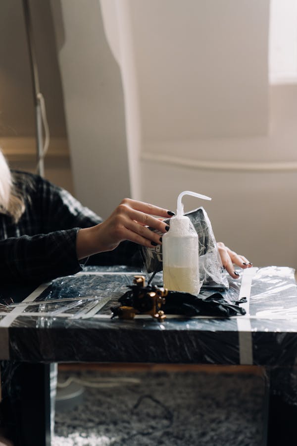 Woman in Black Long Sleeve Shirt Pouring Water on White Ceramic Pitcher