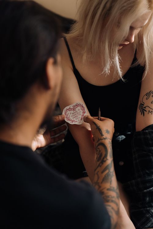 Free A tattoo artist creating a tattoo on a woman's arm, showcasing detailed design work. Stock Photo