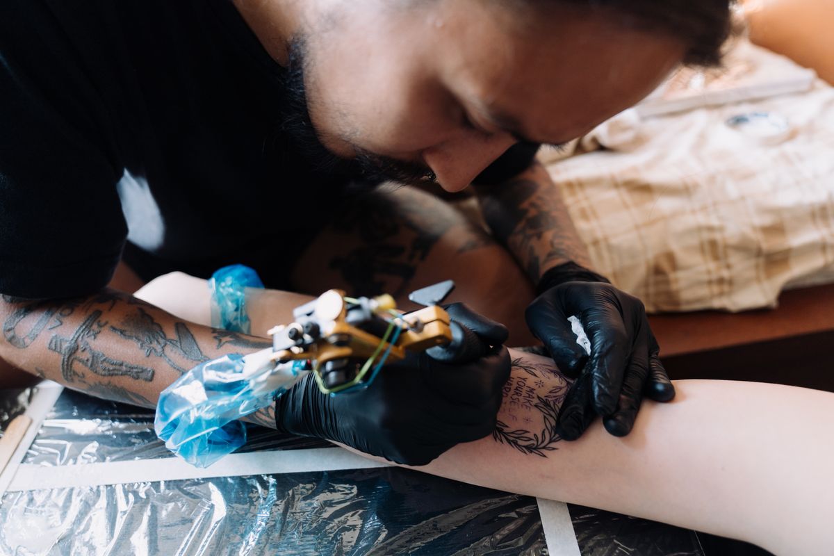 Close-up van een tattoo-artiest die een ontwerp zet op een arm