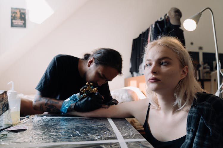 A Blonde Woman Getting A Tattoo On Her Arm 