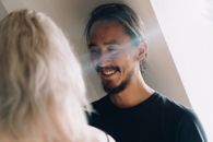 一个留着胡子的男人在室内温暖地微笑，阳光透过窗户照进来