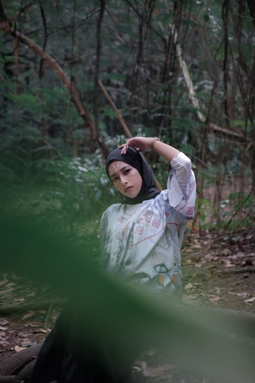 Free Portrait of a woman in a hijab posing elegantly surrounded by a lush forest atmosphere. Stock Photo