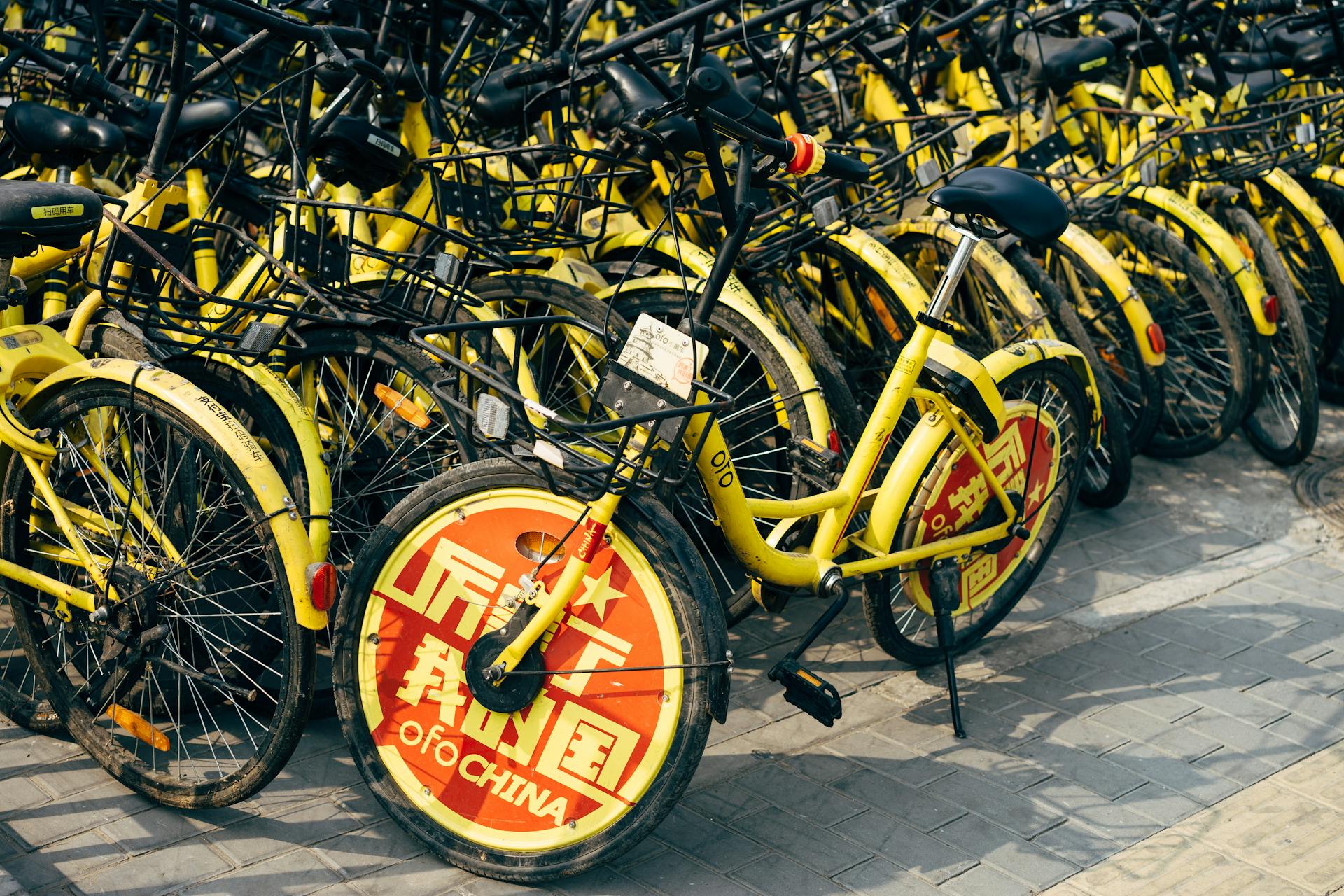 A fleet of yellow shared bicycles parked on a city sidewalk indicating urban mobility solutions.