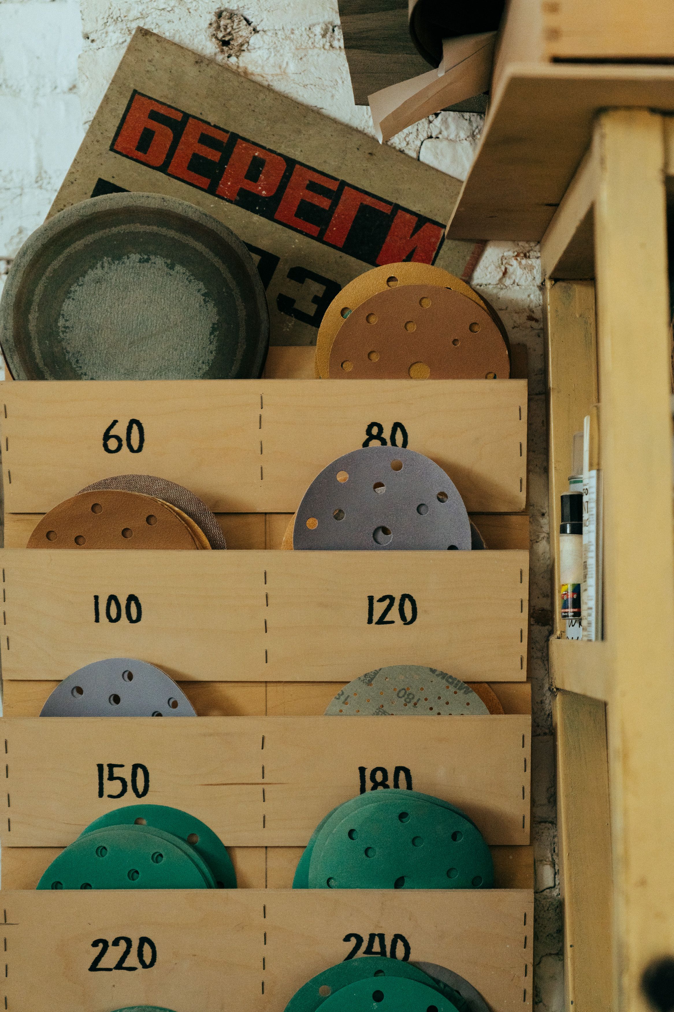 Neatly sorted sanding discs in a rustic workshop setting with a range of grit numbers.