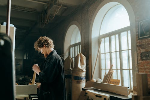 Man in Black Coat Standing Near Window