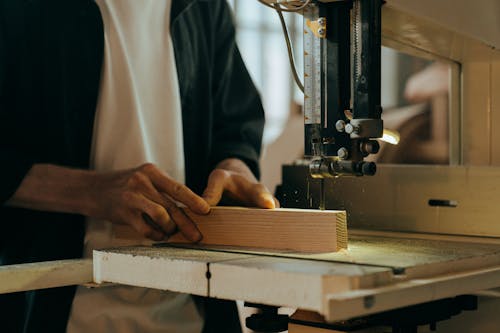 Person in White Long Sleeve Shirt Using Black Sewing Machine
