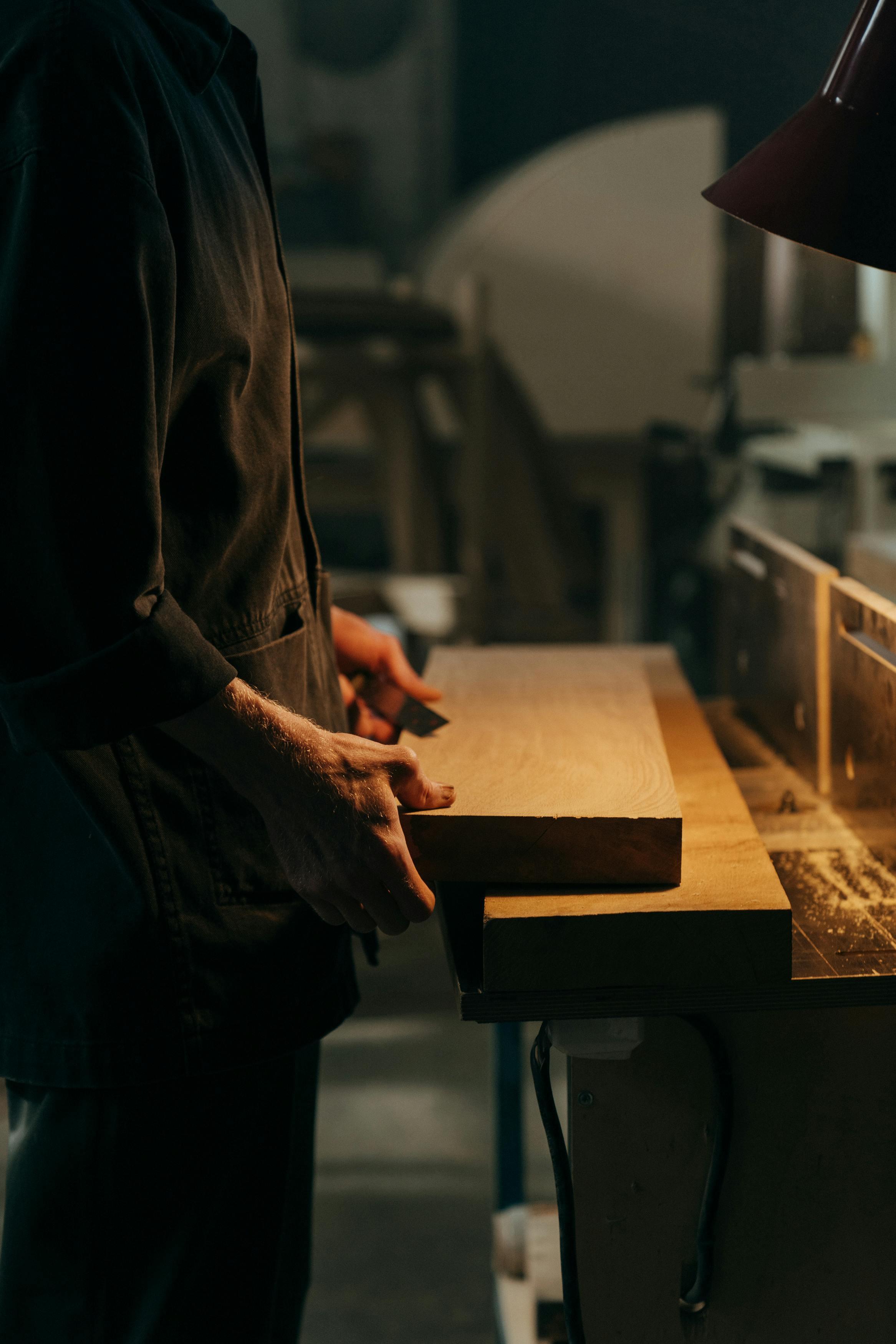 person in black jacket holding brown wooden table