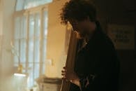 Man in Black Jacket Standing Near Window