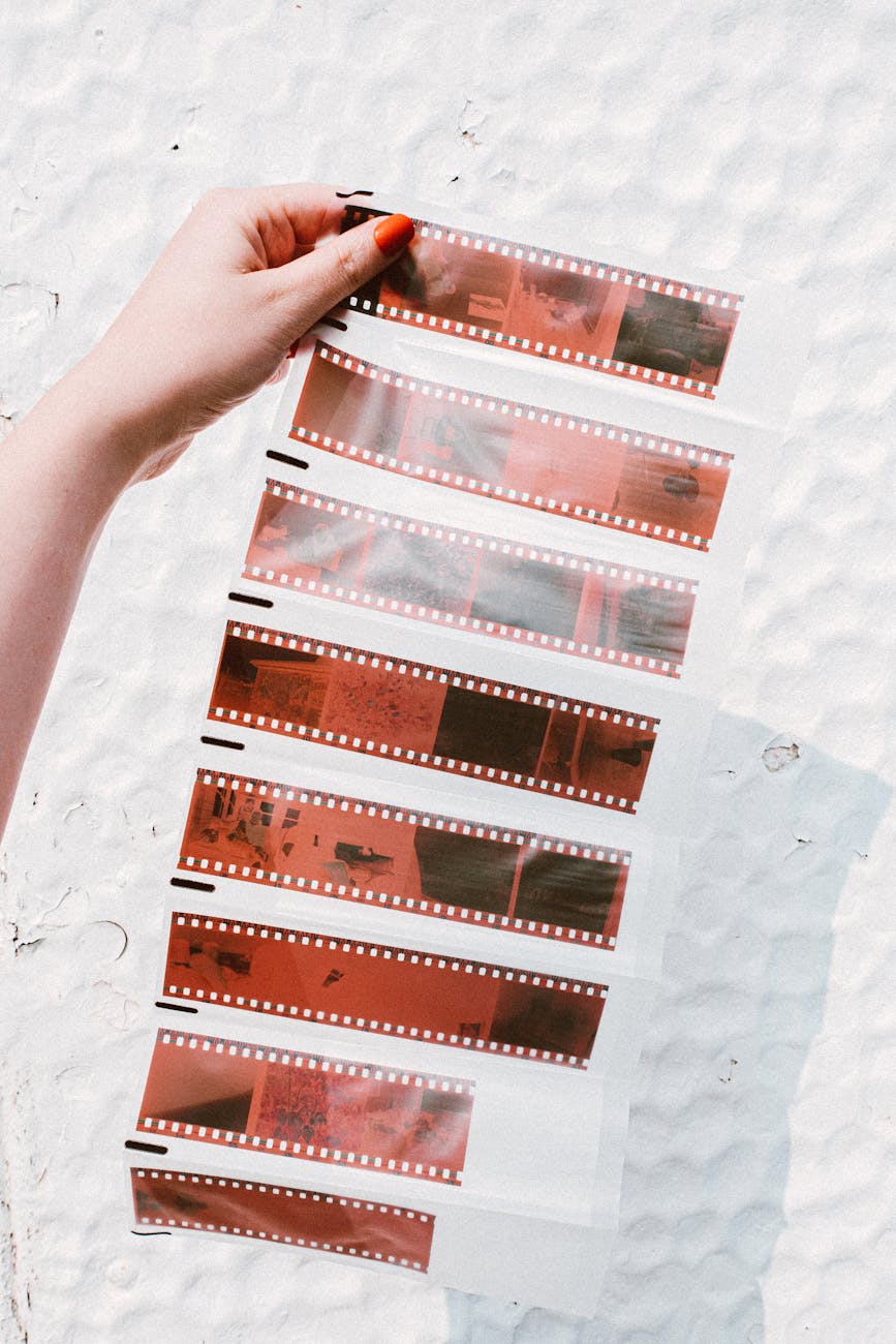 A hand holding film negatives against a textured background in sunlight.