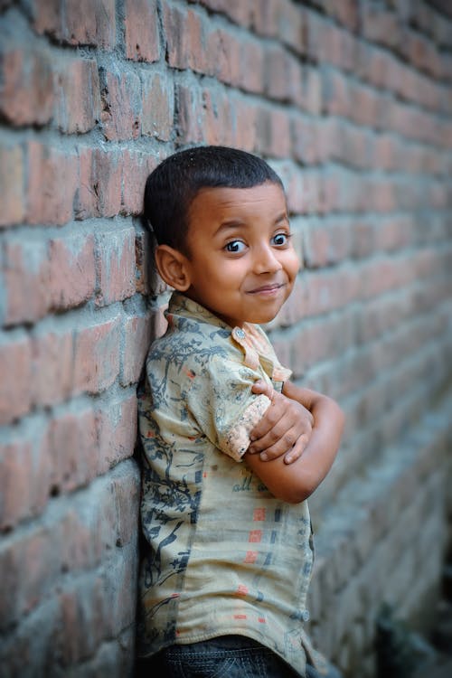 Close-Up Shot of a Happy Boy Leaning on a Brick Wall