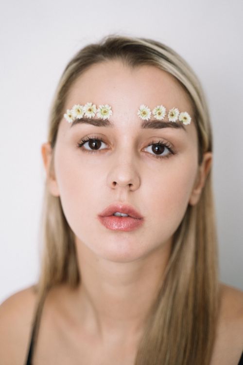 Free Elegant close-up portrait of a woman with flowers on her eyebrows, exuding a fresh and creative vibe. Stock Photo