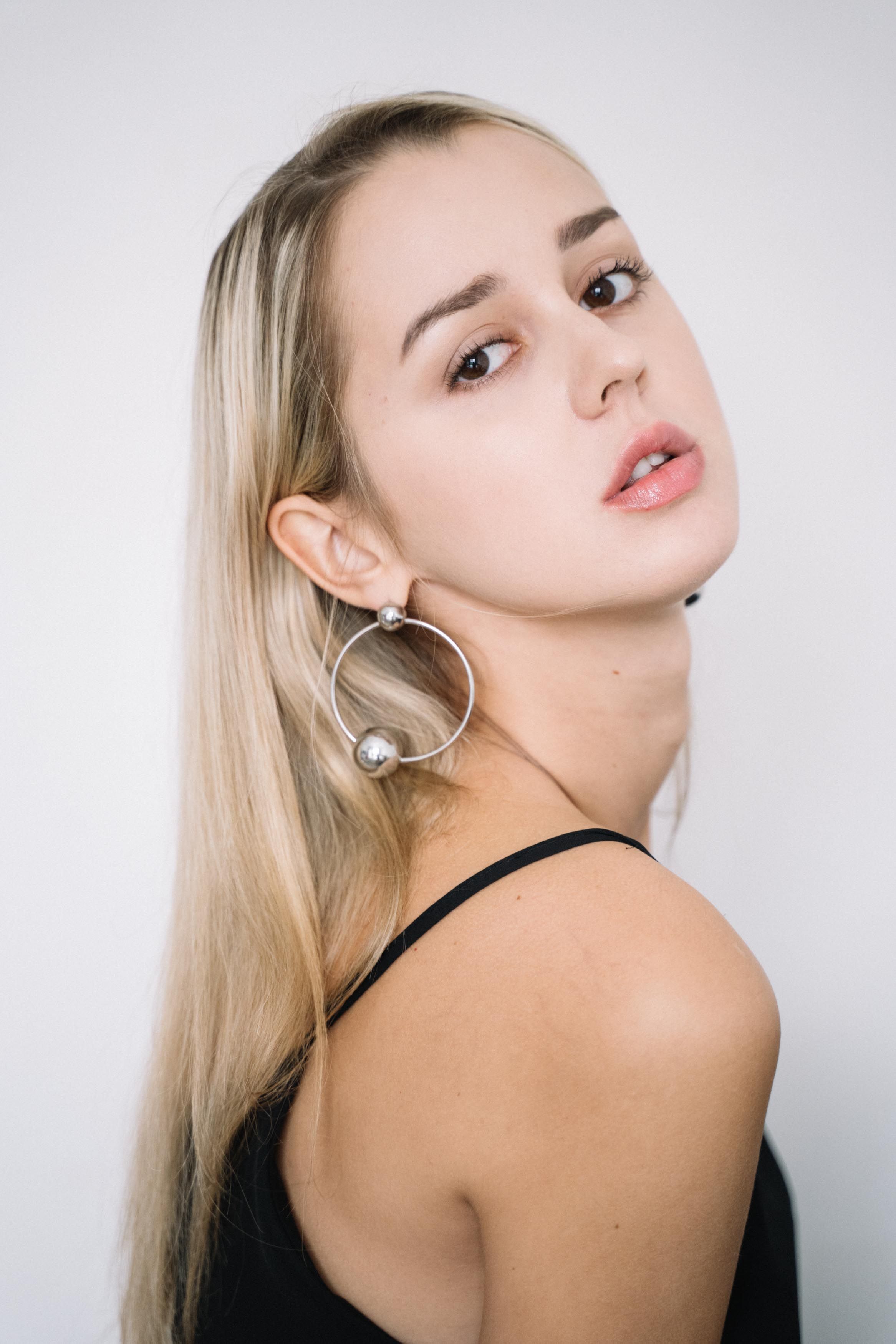 Captivating portrait of a woman with hoop earrings, posing against a white background.