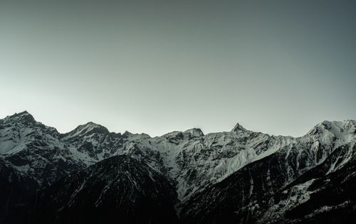 Free A stunning view of snow-covered mountain peaks against a gray sky, captured at dawn, showcasing nature's beauty. Stock Photo