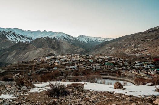 A panoramic view of a small village nestled in a snowy mountain valley during winter.