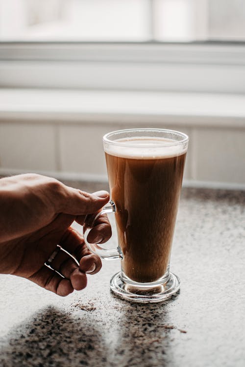 Person Holding Clear Drinking Glass With Brown Liquid