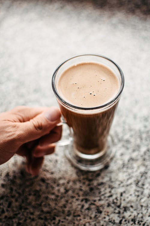 Person Holding Clear Glass Mug With Brown Liquid