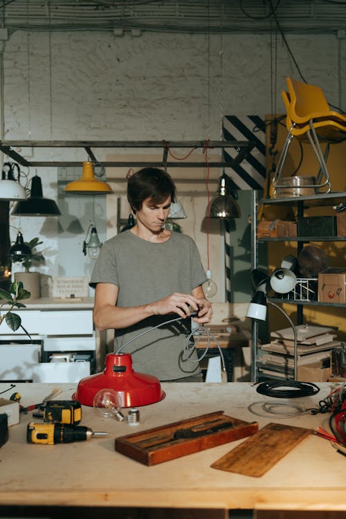 Man in Gray Crew Neck T-shirt Holding Red and Black Power Tool