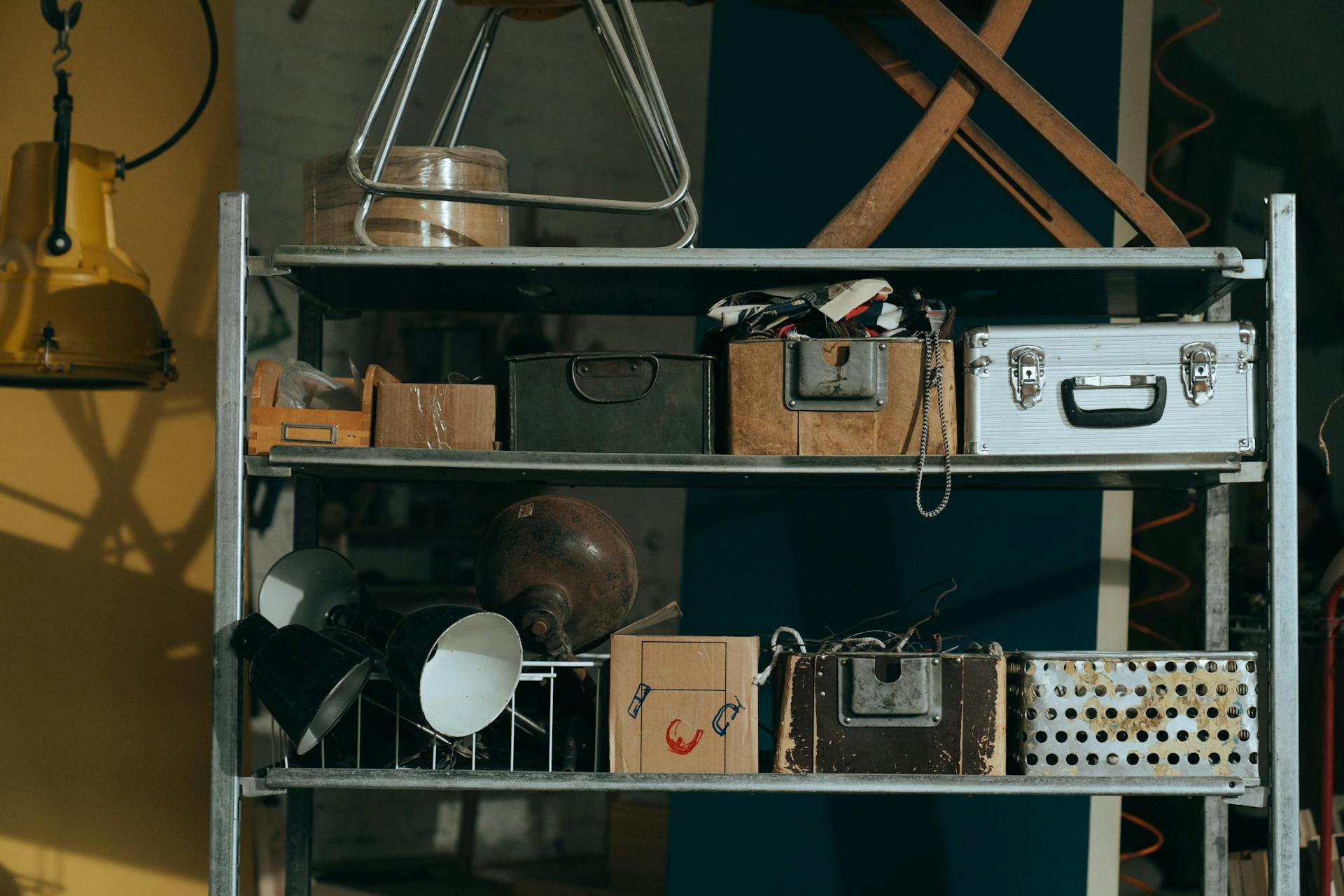 A shelf in a workshop holding vintage and retro objects, showcasing old storage boxes and tools.