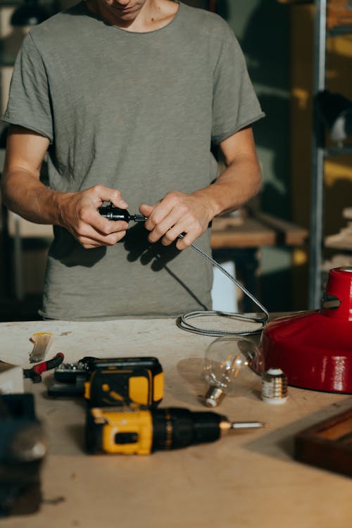 Man in Gray Crew Neck T-shirt Holding Black and Silver Hand Tool