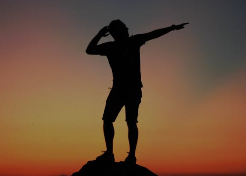 Free Silhouette of Man Standing on Rock during Sunset Stock Photo
