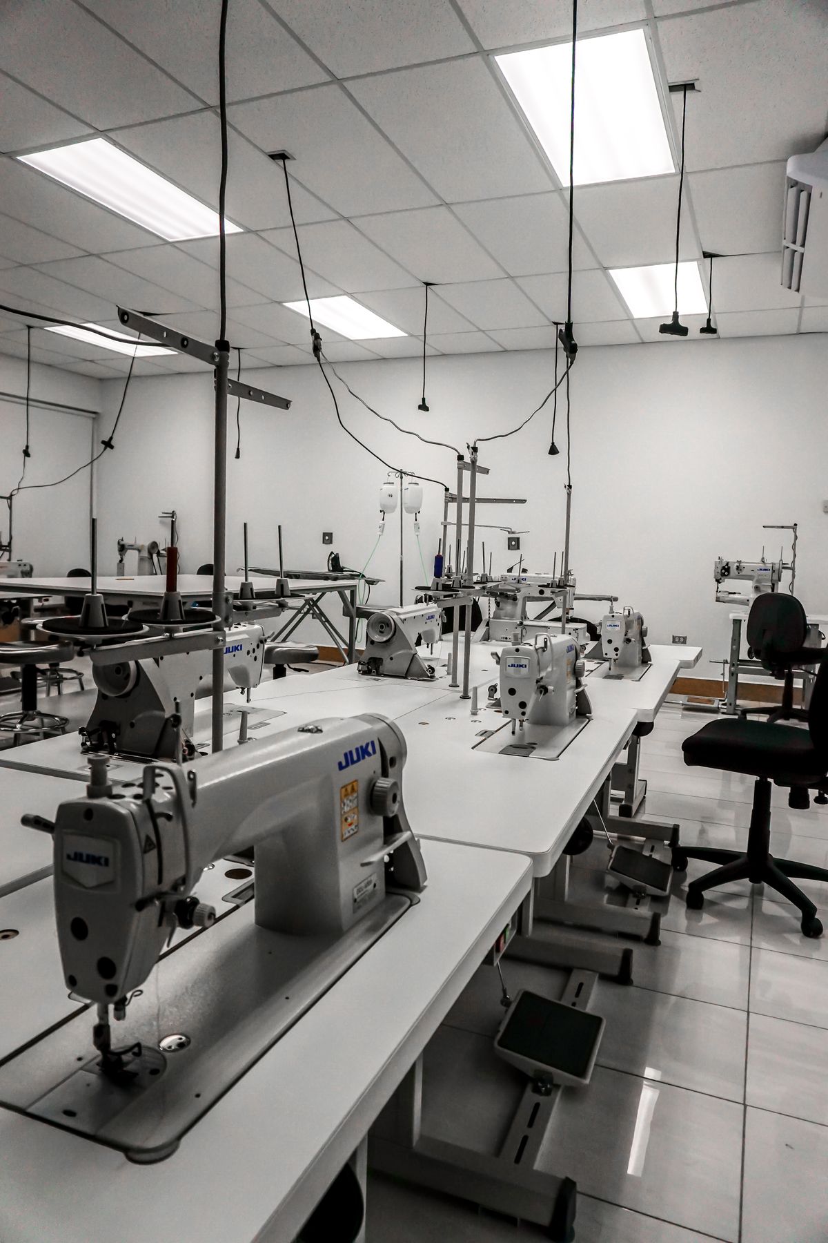 Industrial sewing machines lined up in a well-lit garment factory