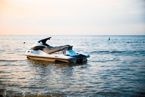 Free A lone jet ski rests on calm ocean waters during a serene sunset. Perfect for travel and leisure themes. Stock Photo