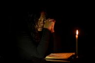 一个女人在烛光下深深沉浸在祈祷中，唤起一种宁静而沉思的心情