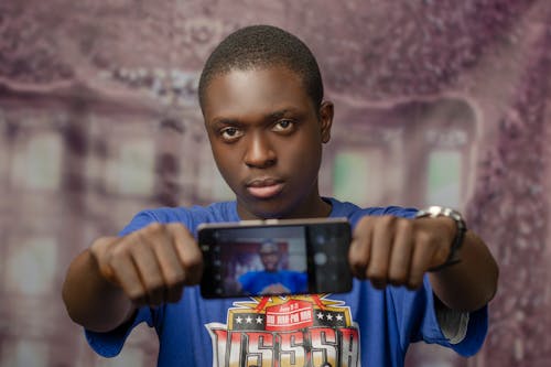 Man in Blue Shirt Holding a Smartphone