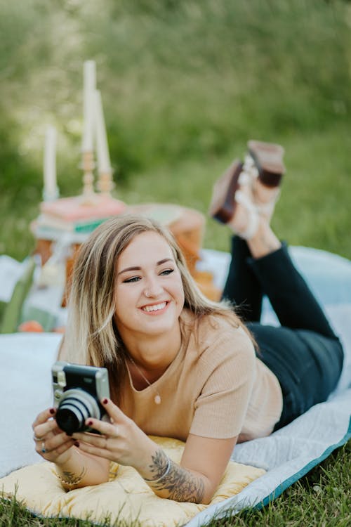 Selective Focus Photo of a Woman Smiling While Holding a Vintage Camera