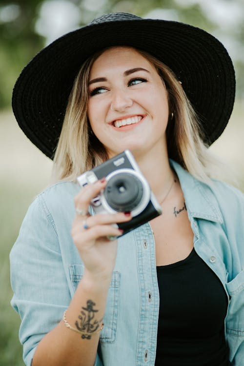 Selective Focus Photo of a Woman Holding a Camera While Smiling