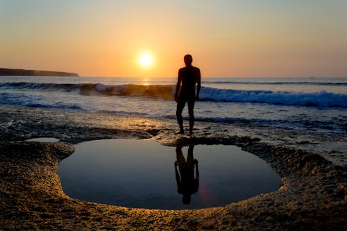 Man Standing on Shore during Sunset