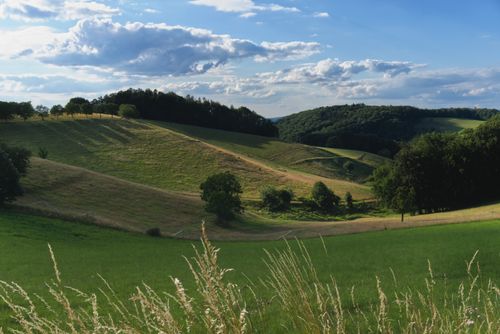 Free Breathtaking view of green hills and fields under a vibrant sky. Stock Photo