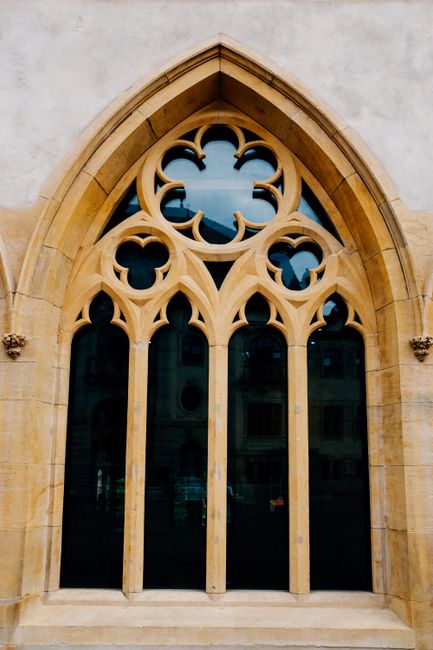 Low angle of arched stained glass window with ornamental elements of aged Gothic cathedral in daylight
