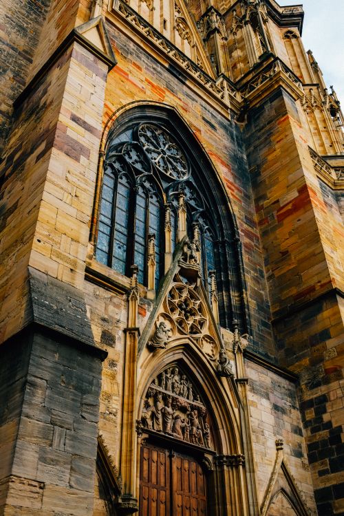 Free From below exterior of aged stone Saint Martin tower with arched window and wooden door located in Colmar city in France Stock Photo