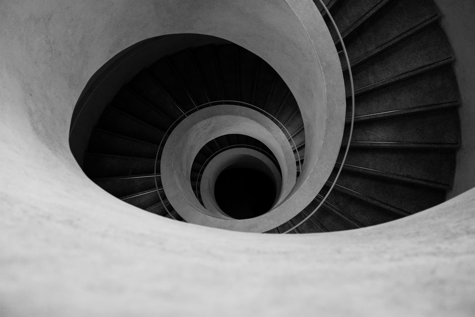 Black and white of background with spiral steps with concrete wide massive walls