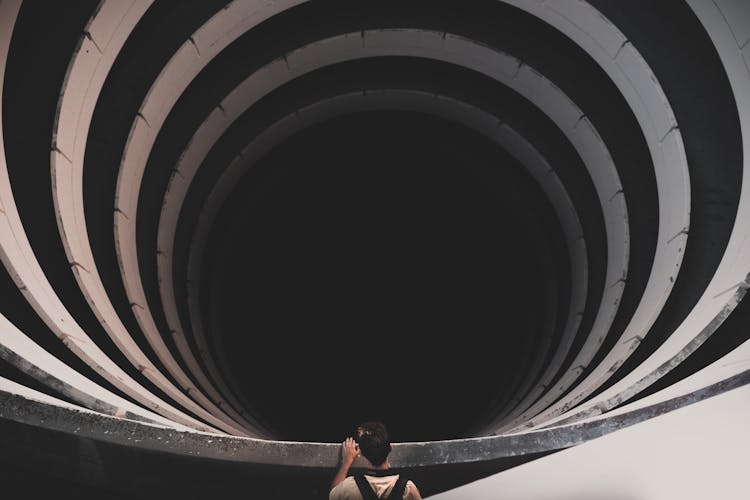 Back View Shot Of A Man Peeking On A Spiral Tunnel