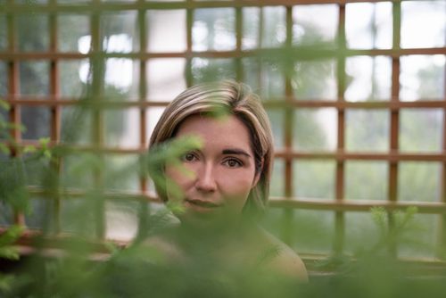 Free Portrait of a woman through lush foliage with natural soft light and green tones. Stock Photo
