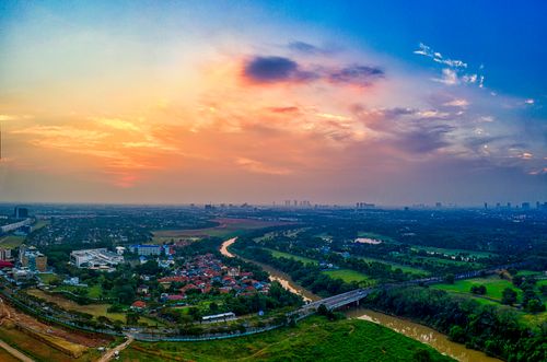 Free A breathtaking aerial view of Banten, Indonesia, showcasing vibrant skies over lush fields and a small town at sunset. Stock Photo