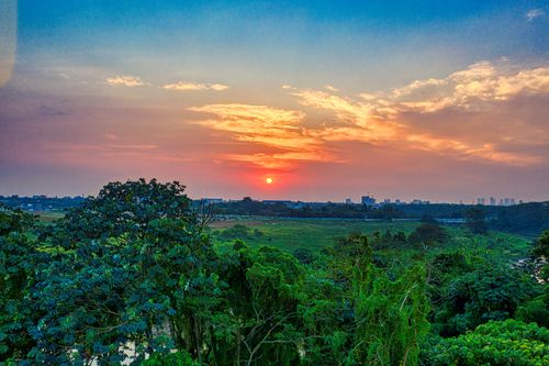 Free Dramatic sunset sky over lush green fields and trees in Banten, Indonesia. Stock Photo
