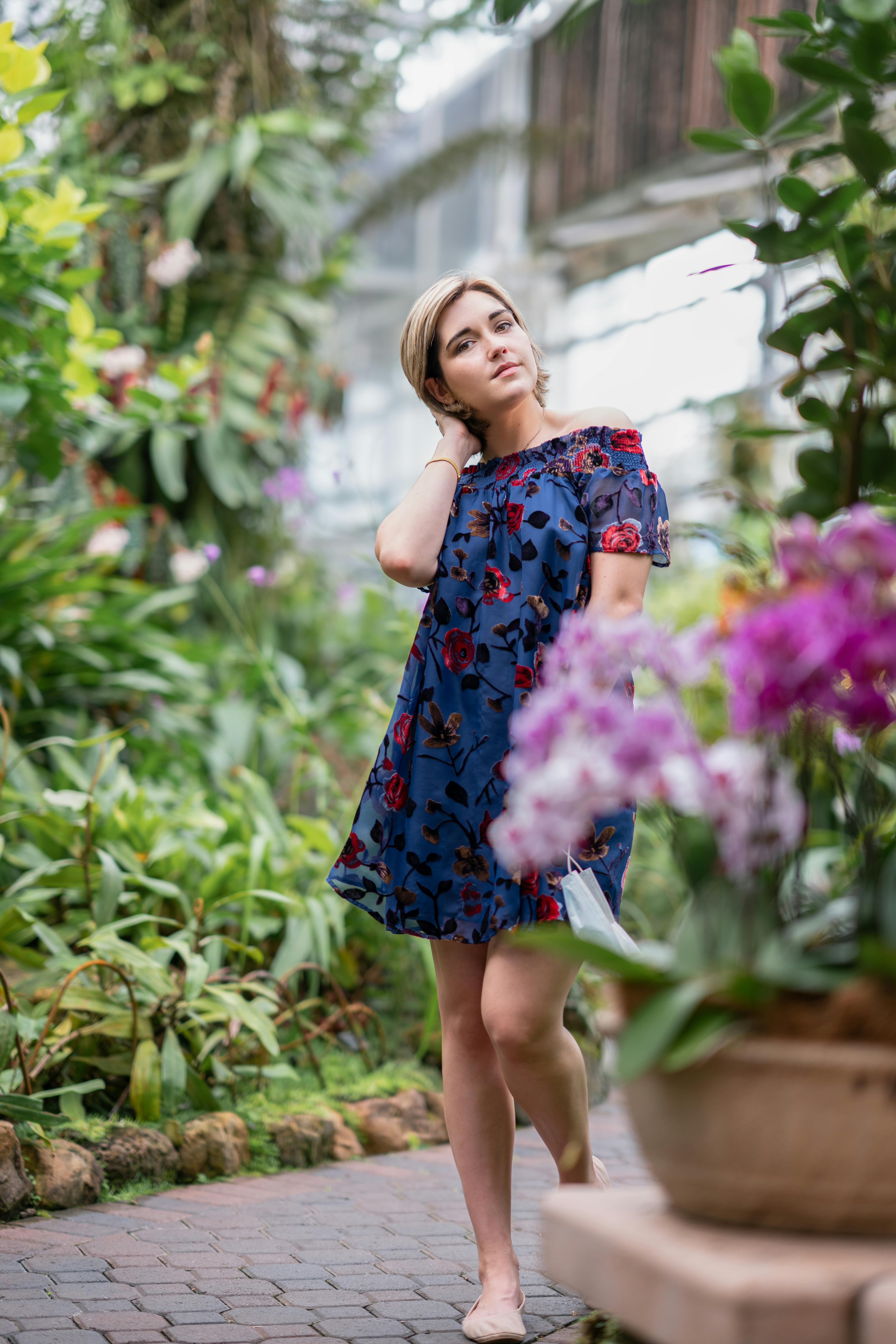 一位穿着花裙的女人穿过生机勃勃、绿意盎然、鲜花盛开的花园