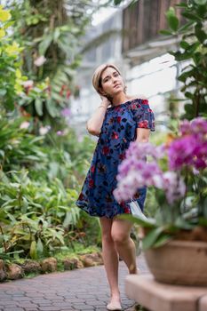 一位穿着花裙的女人穿过生机勃勃、绿意盎然、鲜花盛开的花园