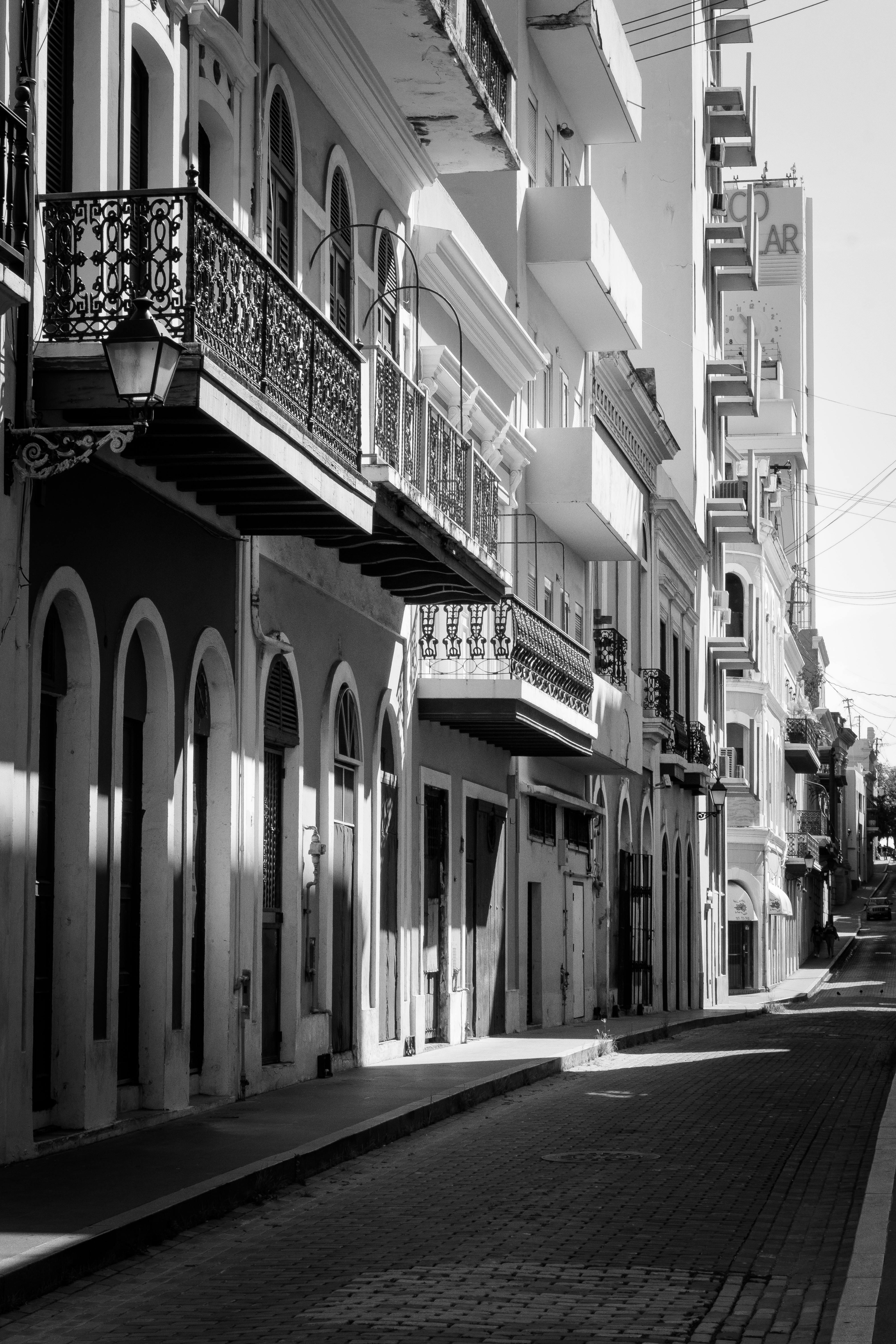 Black and white photo of a European street with classic architecture and ornate balconies.