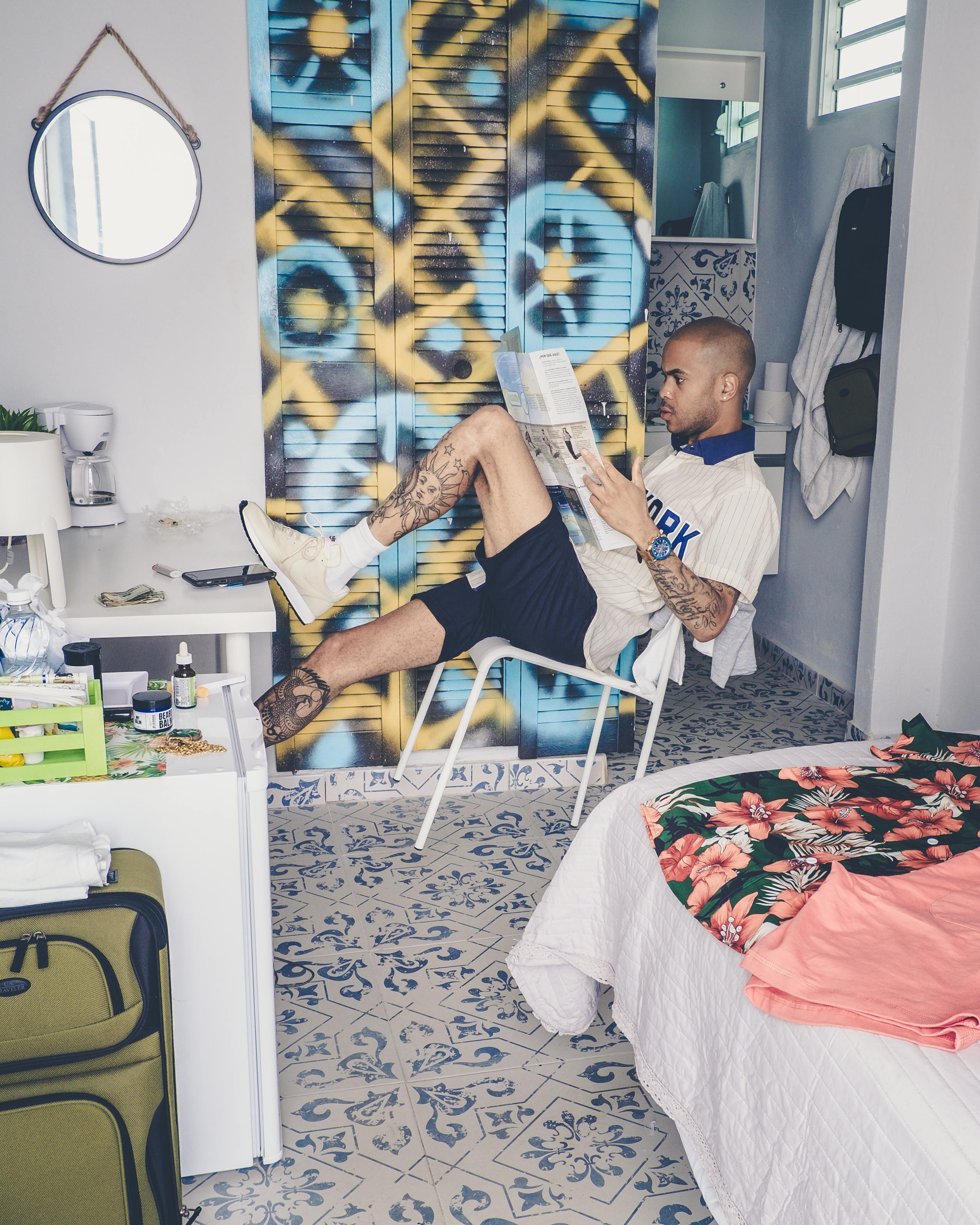 Free Tattooed man reading a newspaper in a stylish modern room, surrounded by urban decor. Stock Photo