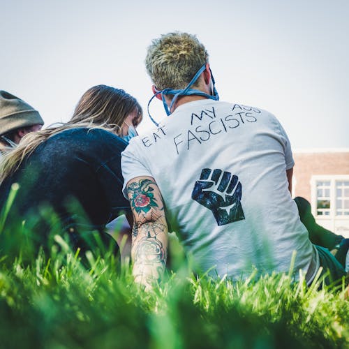 Faceless couple resting on grass while attending antiracist meeting