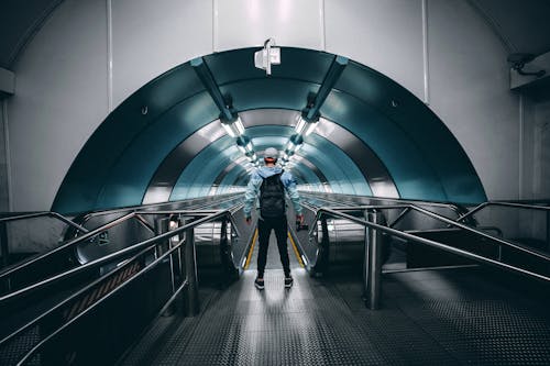 Free Back View of a Person Standing in Front of a Moving Walkway Stock Photo
