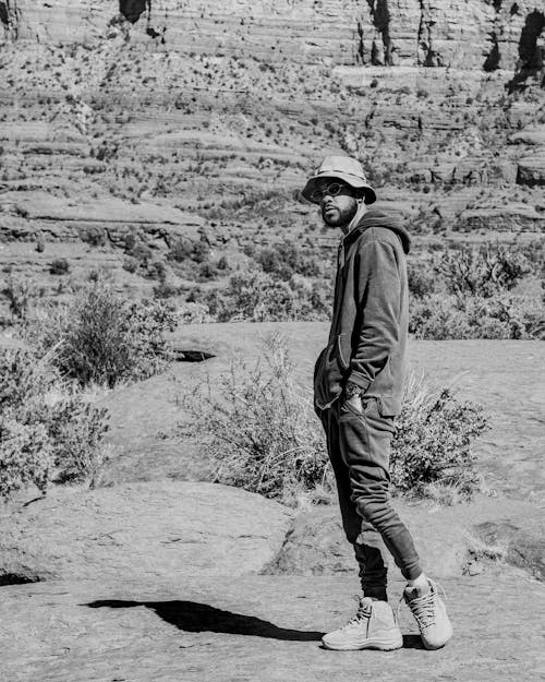 Grayscale Photo of a Man in Bucket Hat Wearing Hoodie Jacket while Posing at the Camera